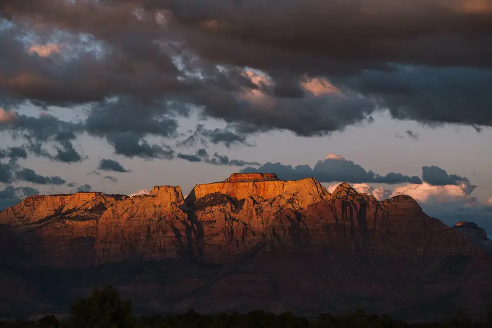 Sandstone mesa catching last light under dark clouds near Hurricane, Utah