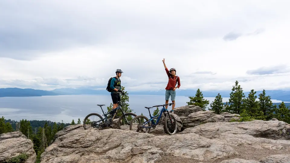 Evan and Melanny with mountain bikes on a ledge above Lake Tahoe