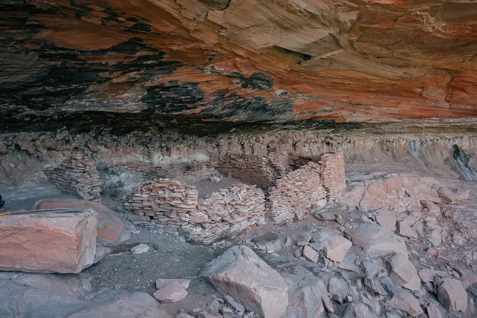 Stacked stone walls of the cliff dwelling under a smoke-darkened alcove roof