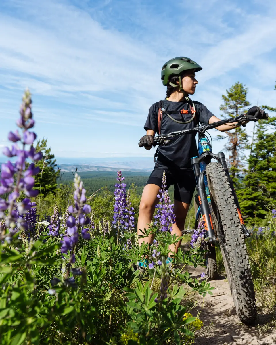 Melanny standing next to purple wildflowers on a trail in Mount Hood, Oregon