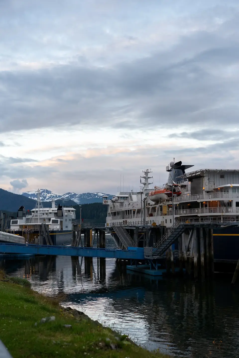 Alaska ferries docked at the Juneau terminal at dusk, snow peaks behind