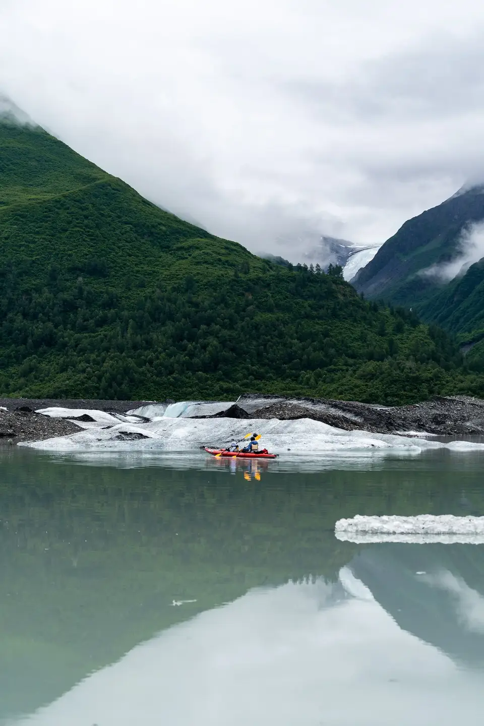 A red packraft threading ice chunks on a glacial lake near Valdez, Alaska