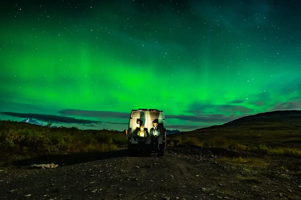 Green aurora over the van, lit from inside, on a dark pullout near Denali, Alaska