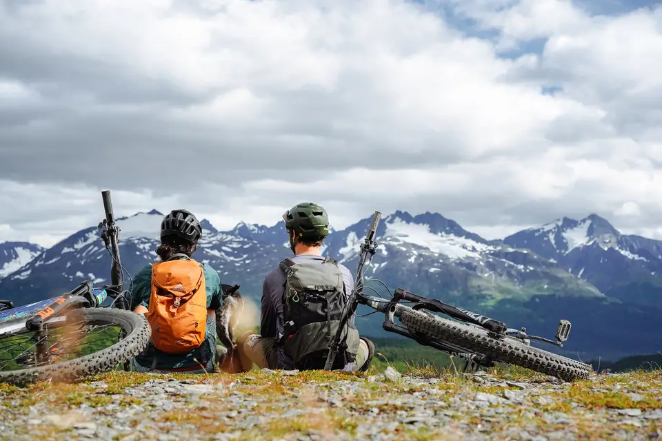 Two riders and a dog with bikes on a ridge near Seward, Alaska