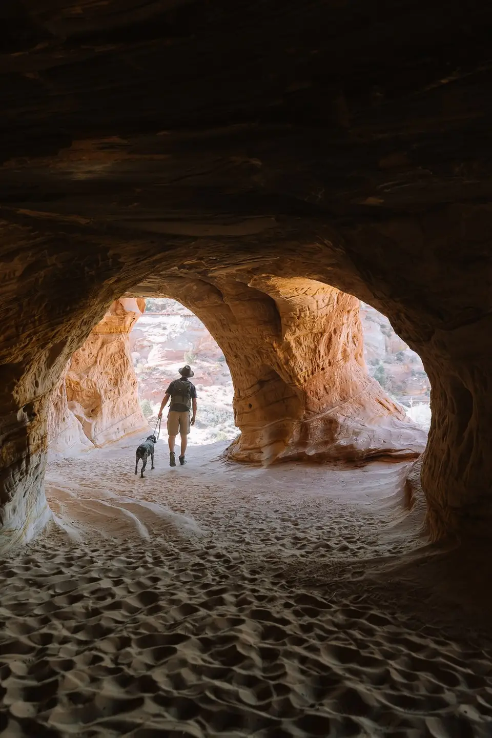 Evan walking Penelope out of a sand cave near Kanab