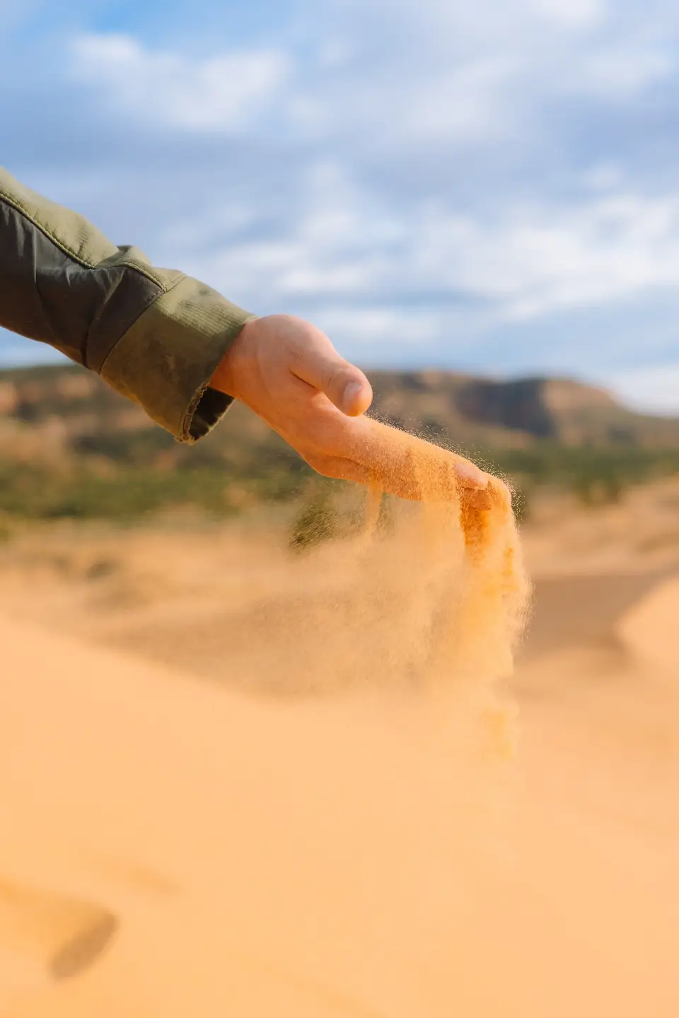 Coral pink sand pouring through a hand at the dunes