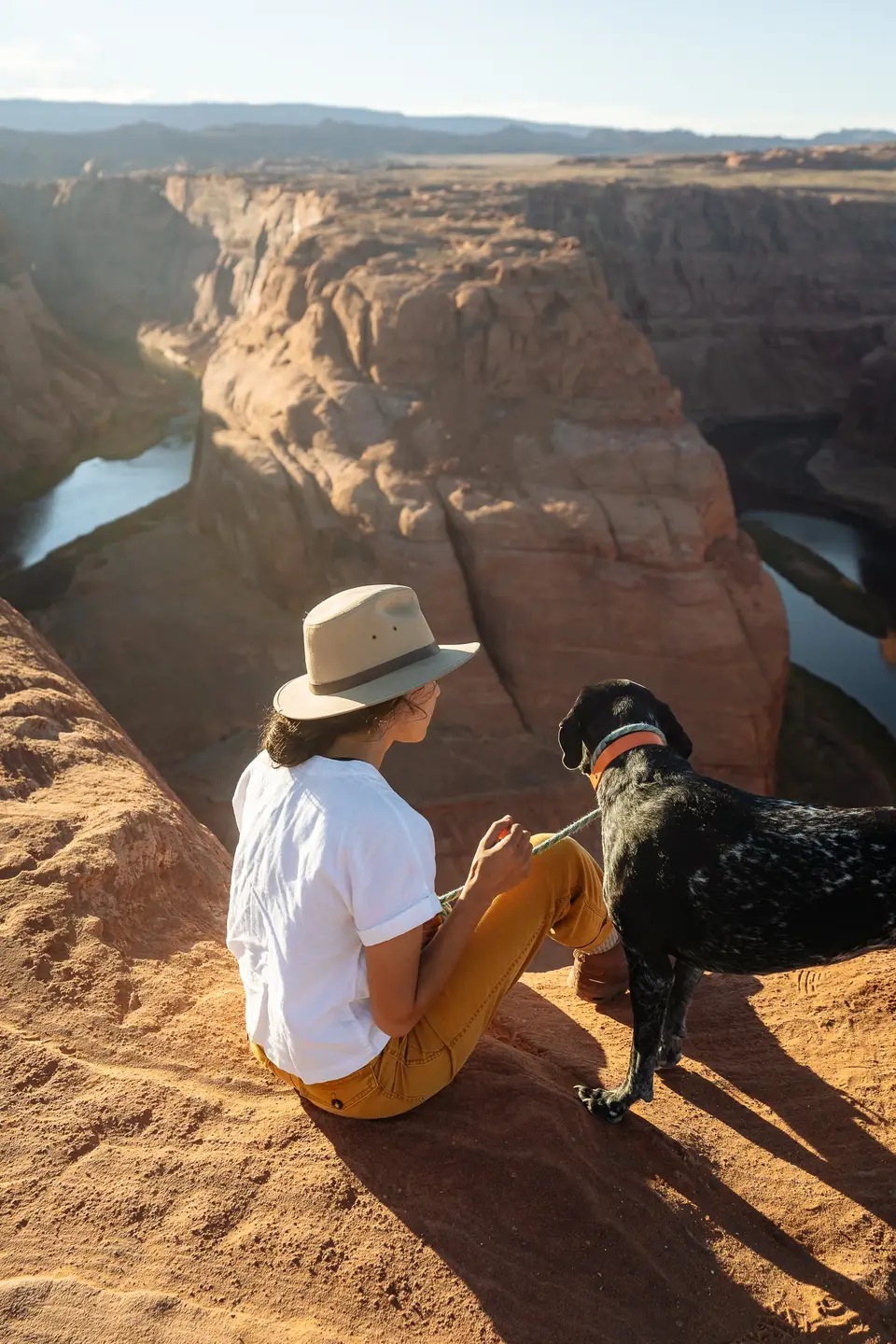 Melanny and Penelope sitting on the rim above Horseshoe Bend