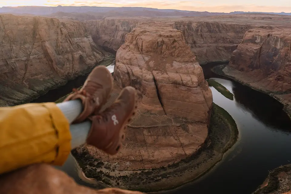 Hiking boots dangling over the edge at Horseshoe Bend