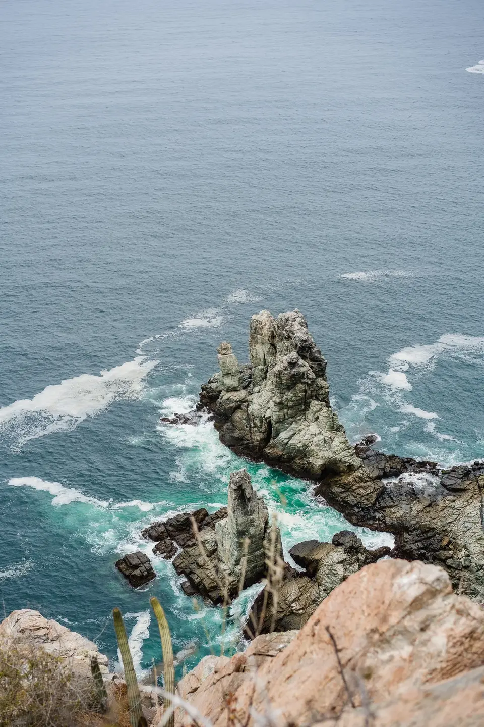 Turquoise surf breaking on dark rock below the cliffs near Todos Santos, Baja California Sur