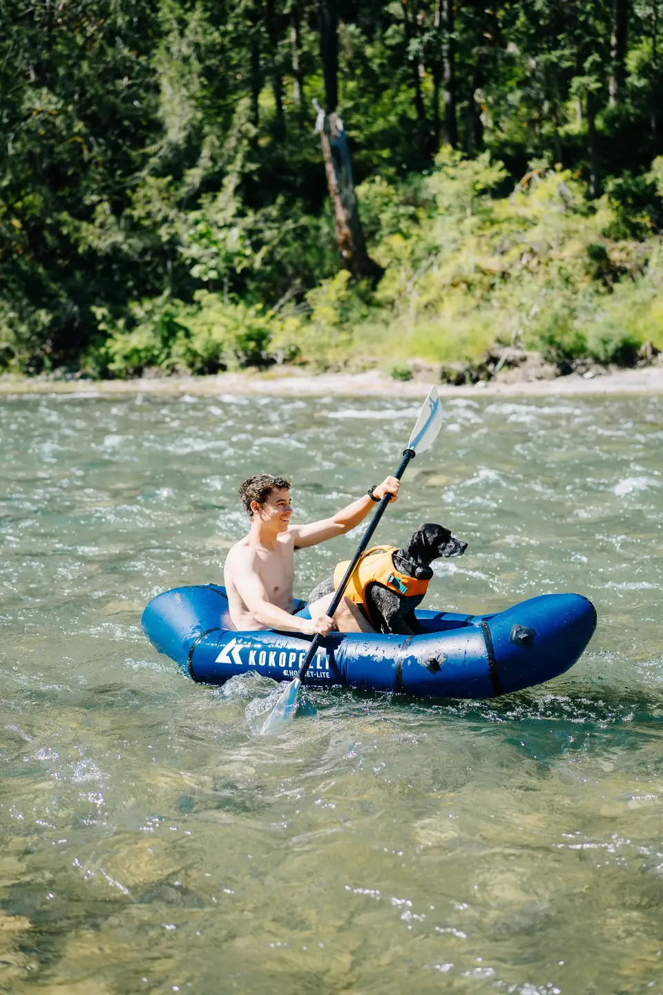Paddling a blue packraft through clear, stony river water near Lake Cowichan, Vancouver Island