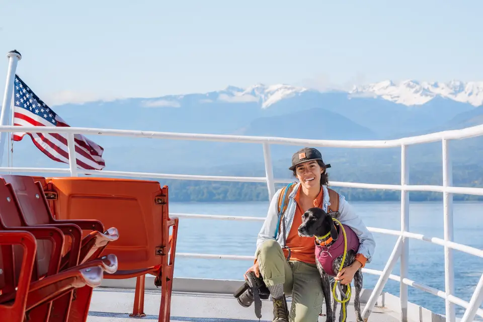 Melanny and Penelope on the ferry deck, US flag and snow peaks behind them