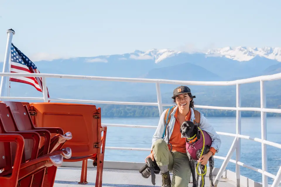 Melanny kneeling on the Coho ferry deck with Penelope and a camera