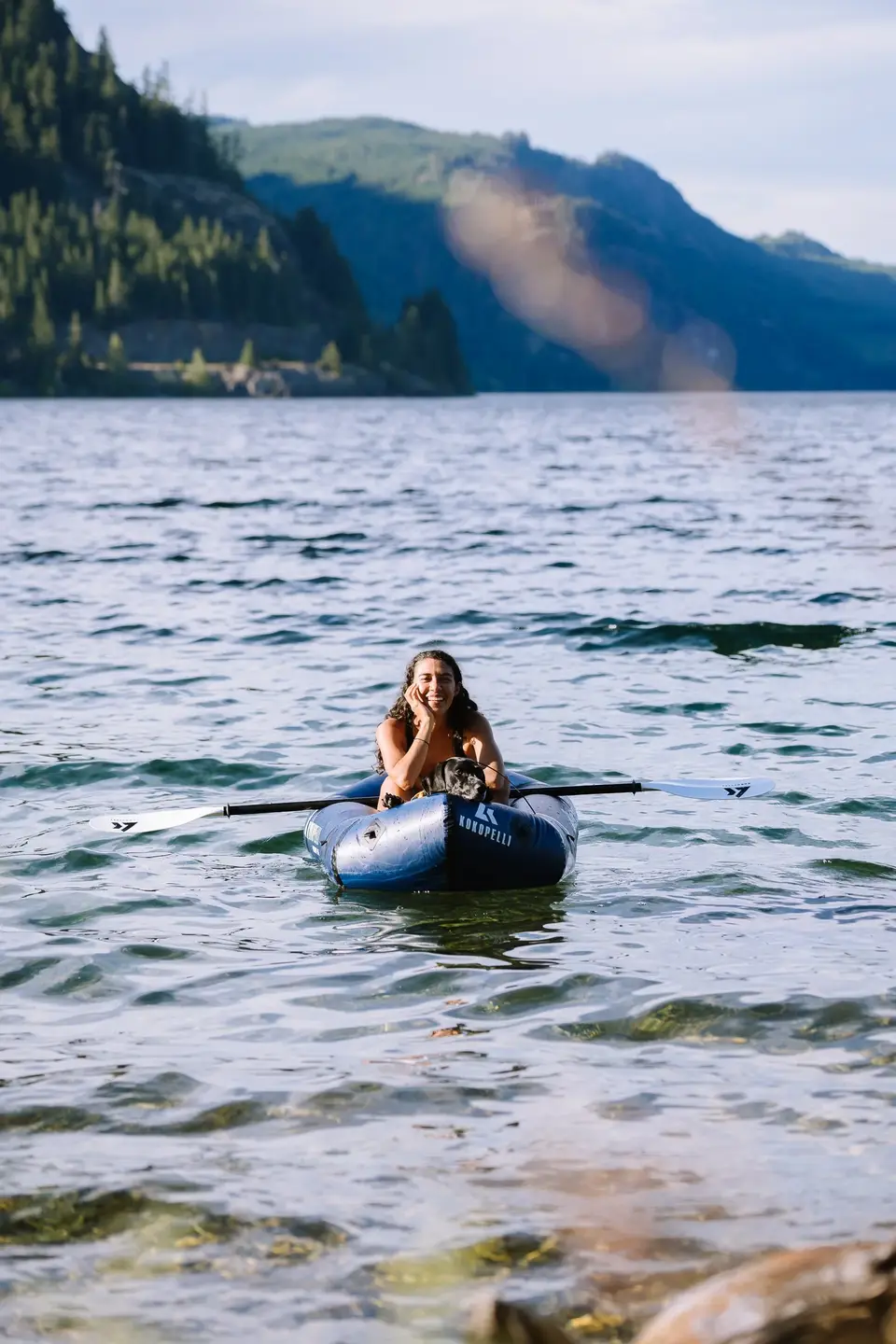 A packrafter on a calm lake with forested mountains behind, Campbell River, Vancouver Island
