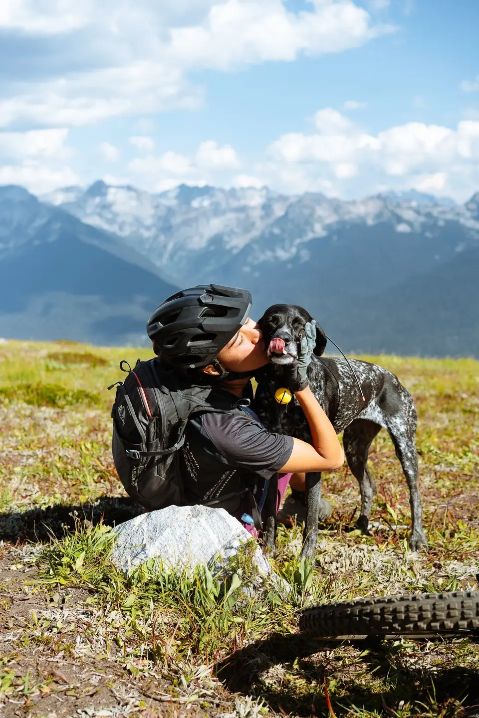 Melanny in a helmet kissing Penelope in a meadow near Revelstoke, British Columbia