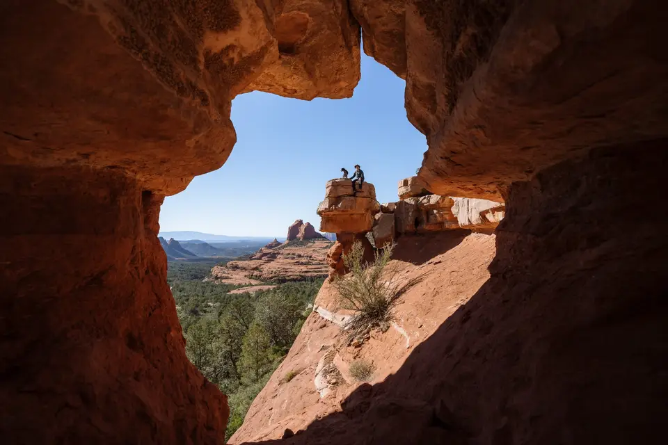 Evan and Penelope sitting on the rock stack. Photographed from inside the cave/rock opening.