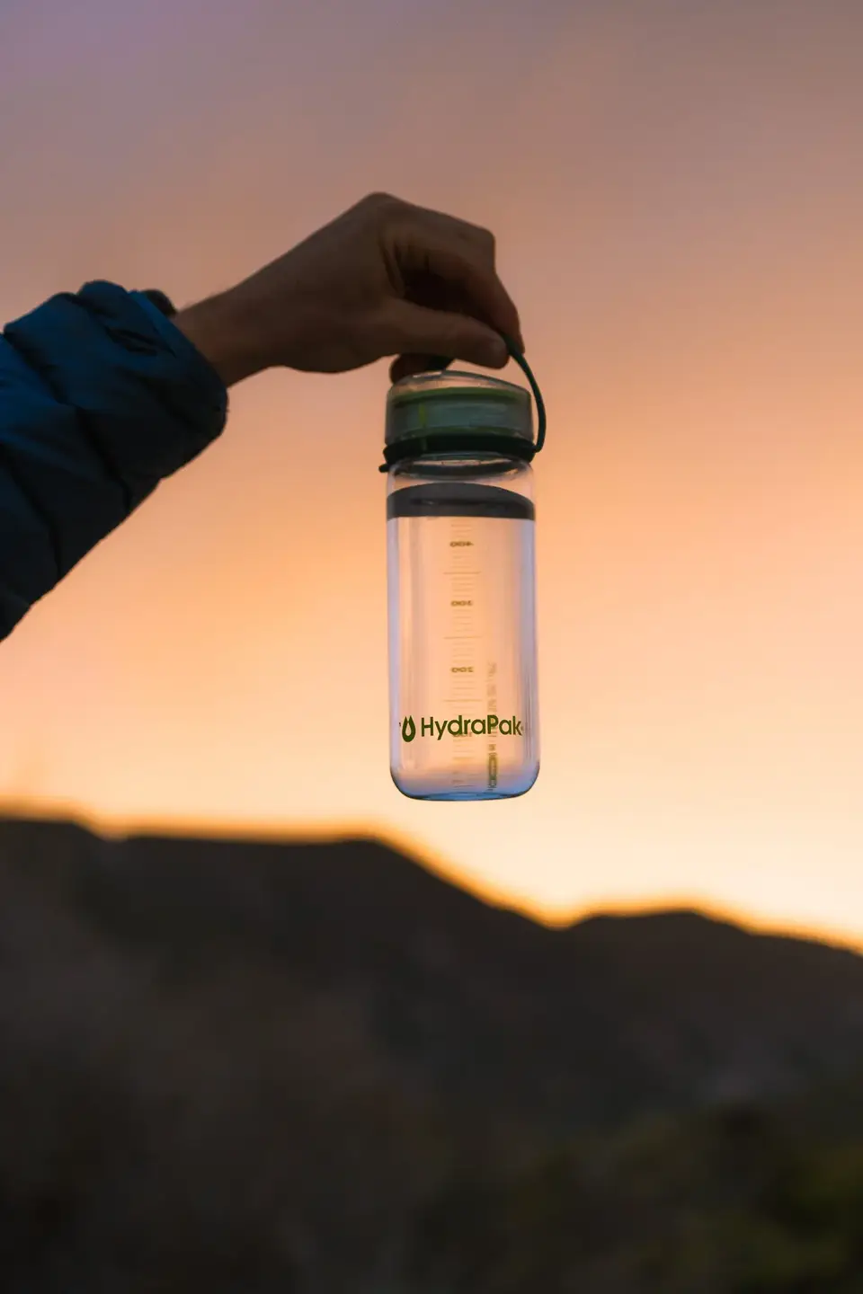 A HydraPak bottle held against a Baja sunset