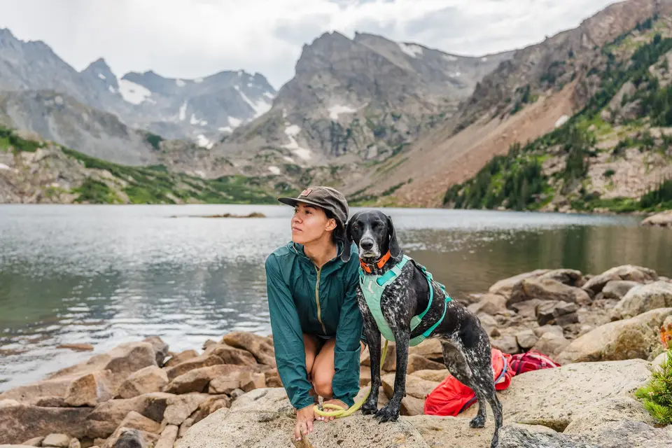 Melanny and Penelope in a teal harness on the rocks of an alpine lake in the Colorado Rockies