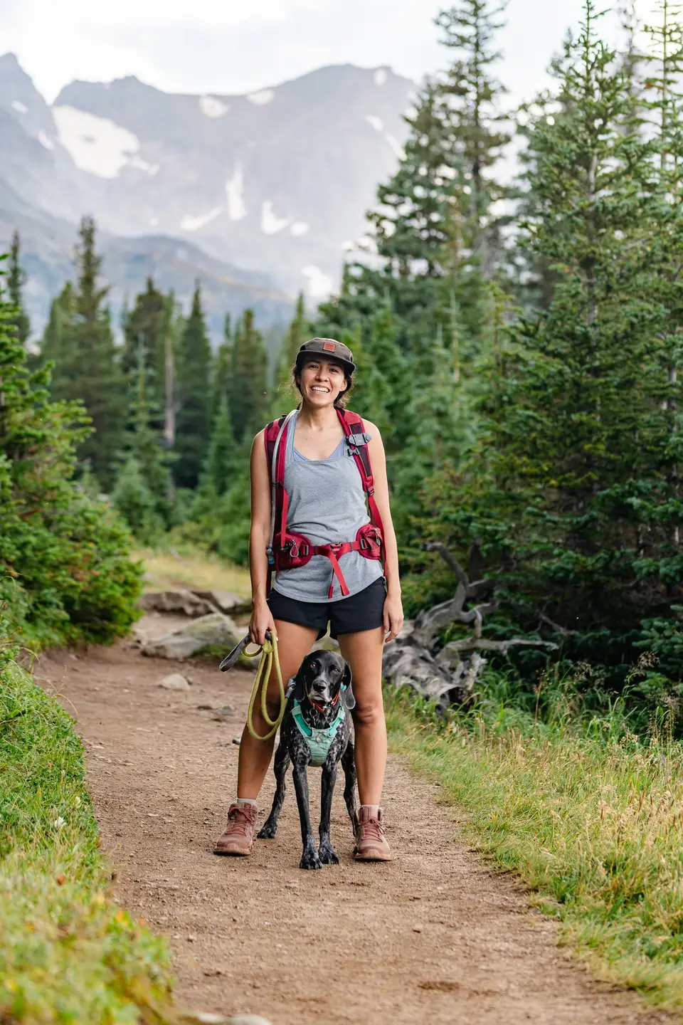 Melanny and Penelope on a forest trail below snowy peaks in the Colorado Rockies