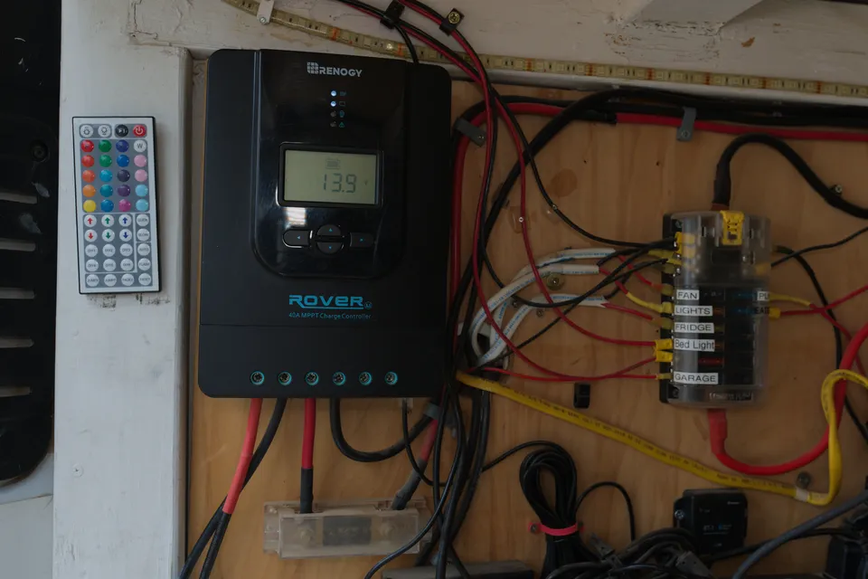 Renogy solar charge controller and fuse block wired on a wood panel in the back of the van