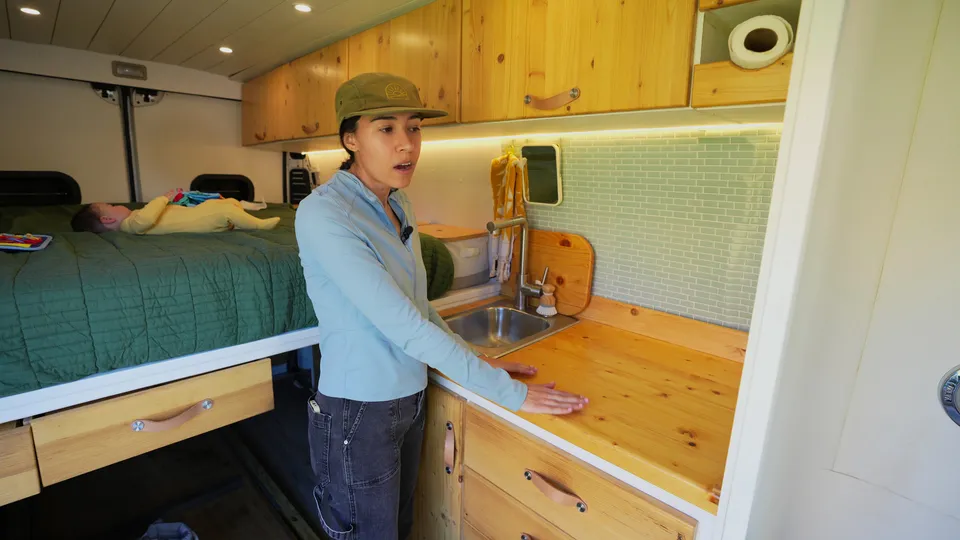 Melanny standing at the van kitchen counter next to the sink