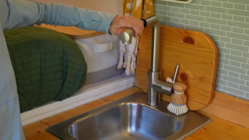 Stainless sink with a pull-out bar faucet, cutting board and dish brush