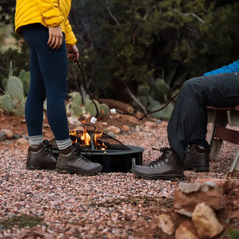 Marshmallows roasting over a fire pit on red gravel, prickly pear behind